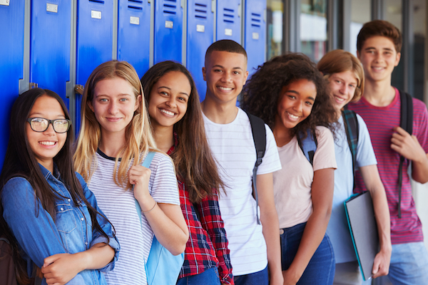 A photo of high school students leaning against hallway lockers.